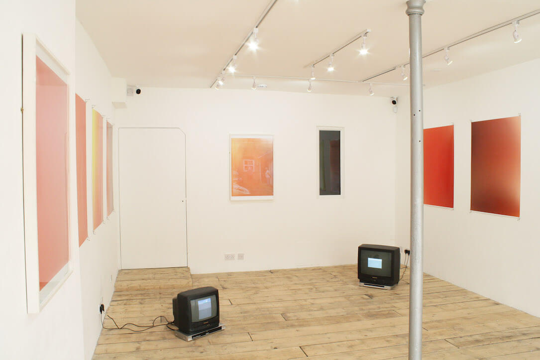 Seven prints are fixed to white walls inside a gallery. There are two televisions on the floor plugged into wall sockets. Fine Art Gallery in London. Collectable art in Penge.